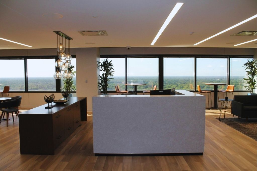 Büro-Immobilien Moderner Empfangsbereich mit weißem Tresen, Holzdetails und Panoramafenstern mit Blick ins Grüne – Symbol für gepflegte Objektästhetik und hochwertige Betreuung