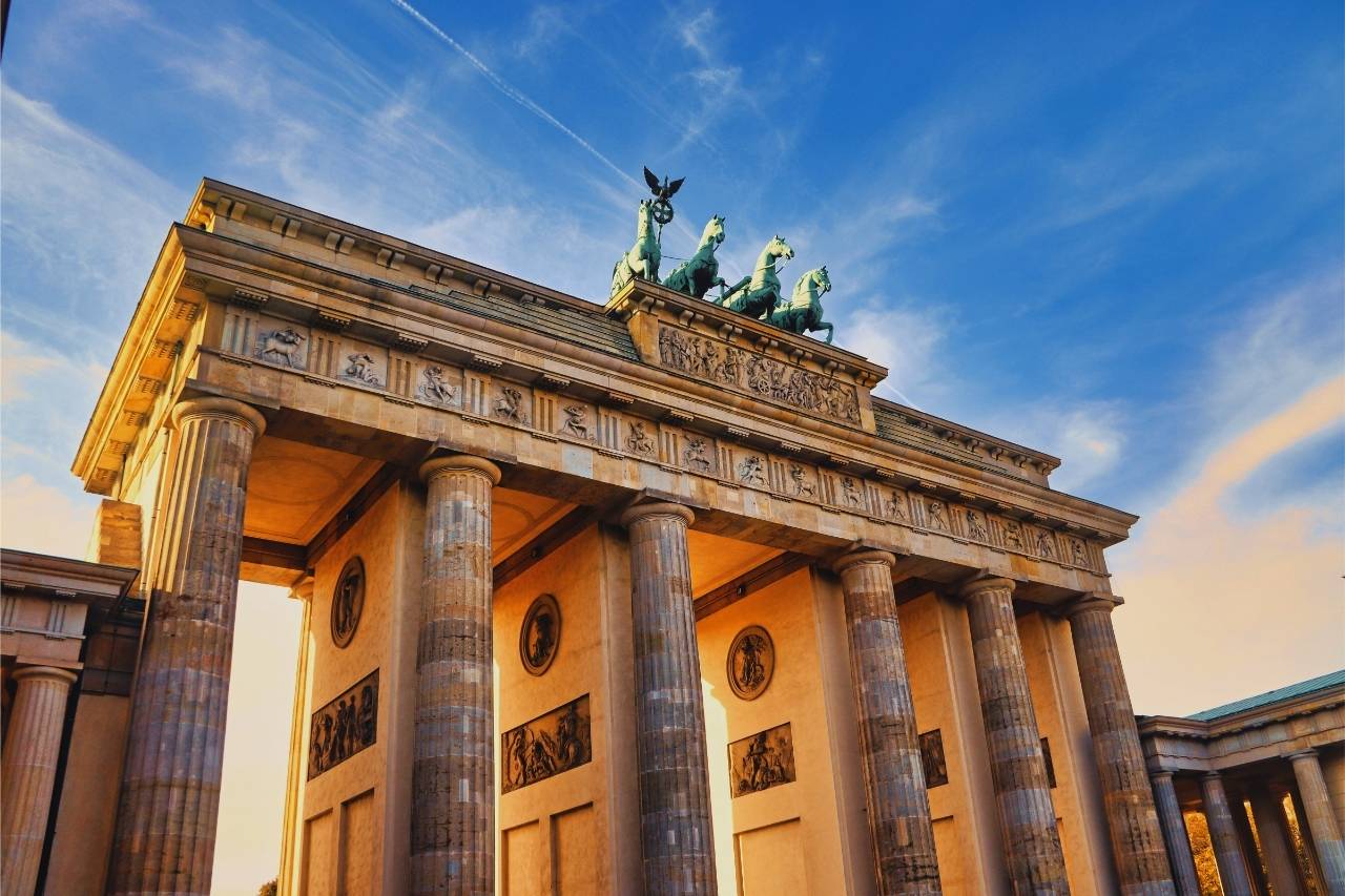 Brandenburger Tor in Berlin bei Sonnenschein, mit Quadriga und blauem Himmel im Hintergrund