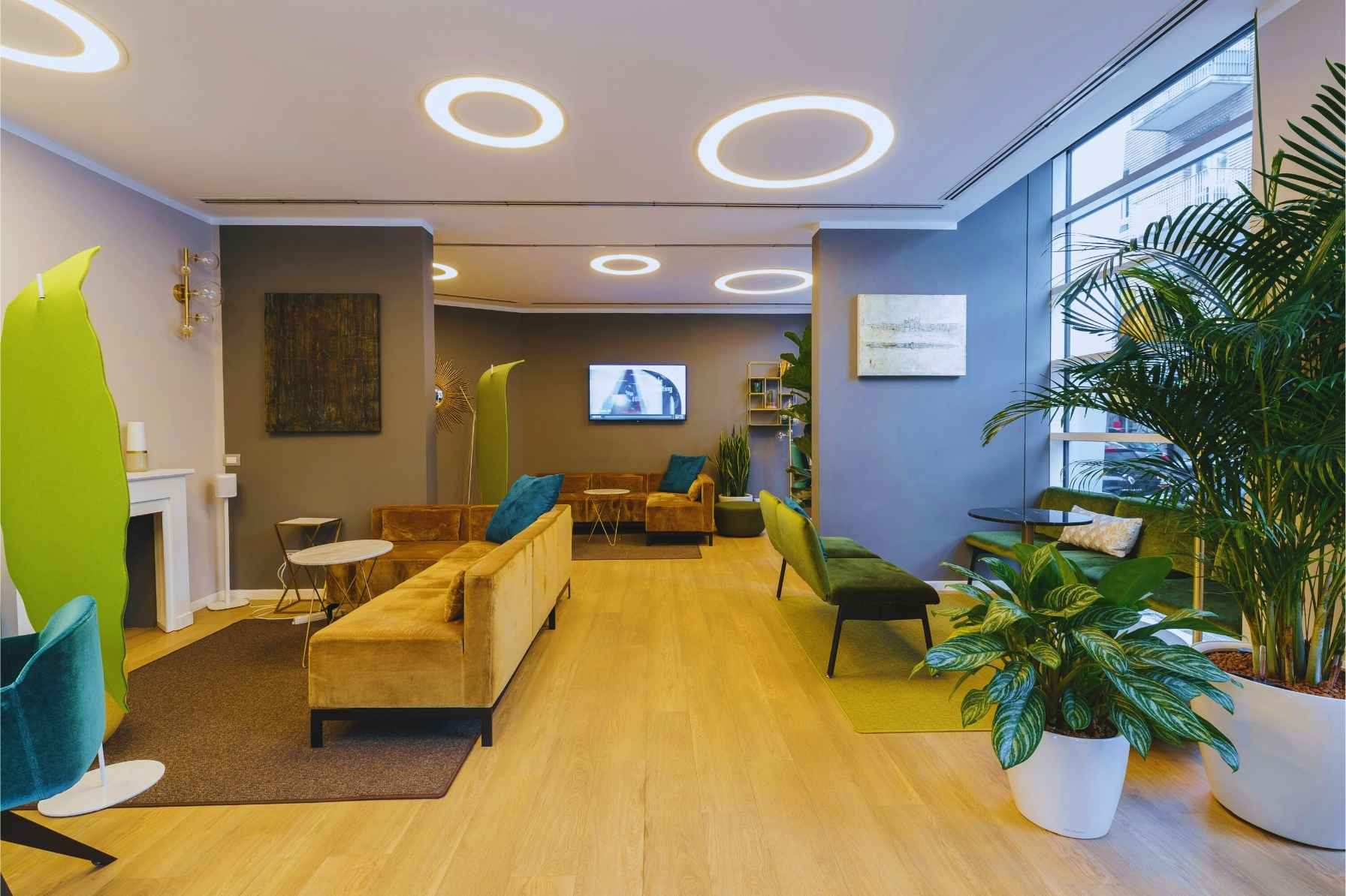 Öffentliche-Bereiche Moderner Wartebereich mit farbigen Sitzmöbeln, Holzboden und Wandkunst – gepflegte Büroeinrichtung in kommerziellem Objekt.