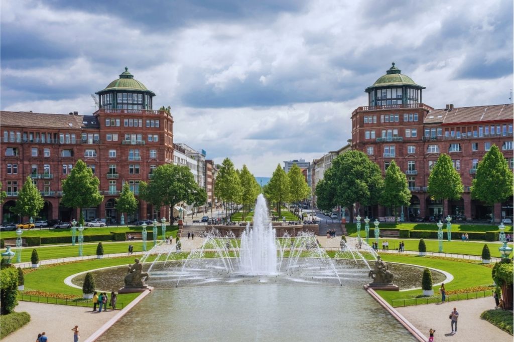 Historischer Wasserturm Mannheim mit Springbrunnen und symmetrischer Parkanlage bei bewölktem Himmel.