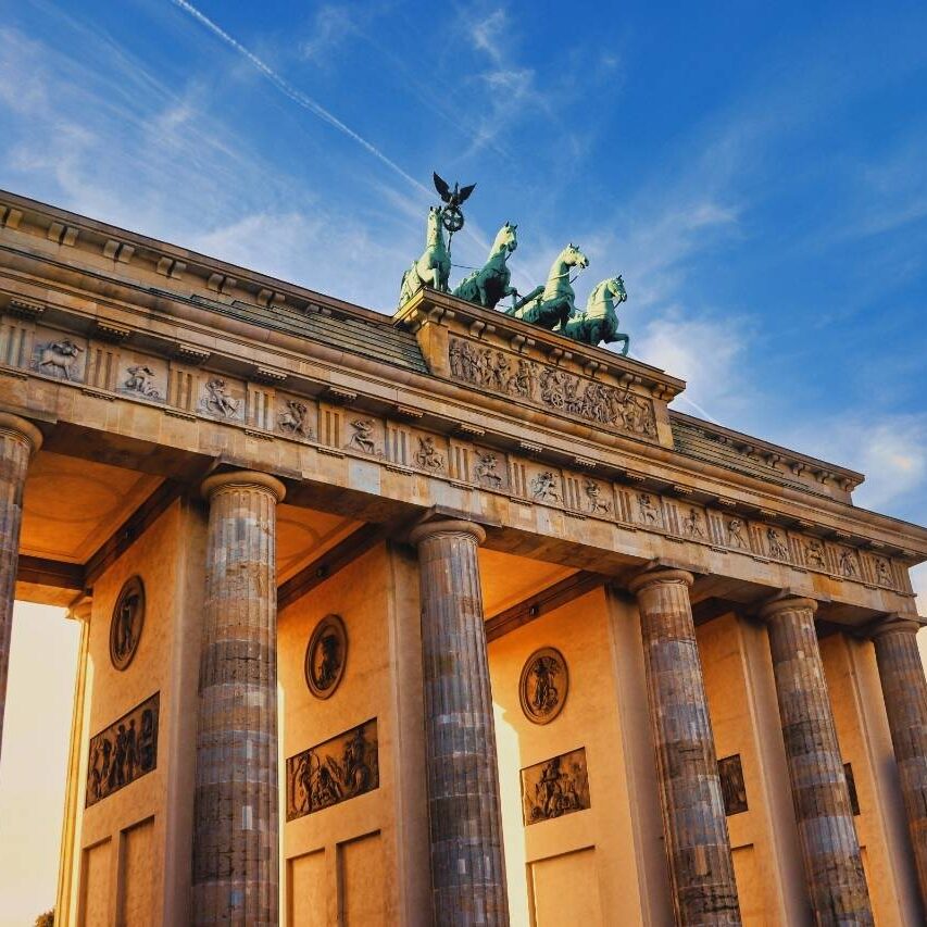 Lacidem Brandenburger Tor in Berlin bei Sonnenschein, mit Quadriga und blauem Himmel im Hintergrund