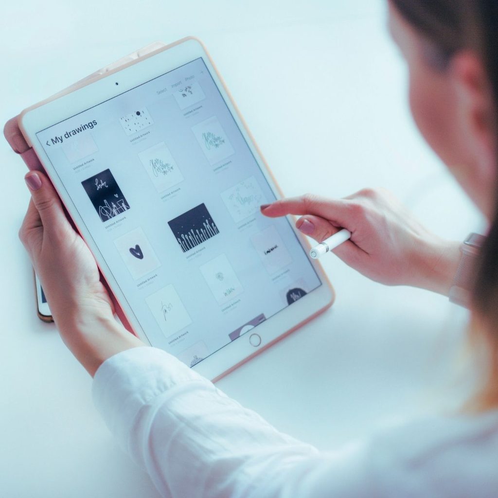 Hand tippt auf ein Tablet mit geöffneten Dateien und Symbolen, als Darstellung digitaler Arbeitsprozesse und moderner Bewerbungswege